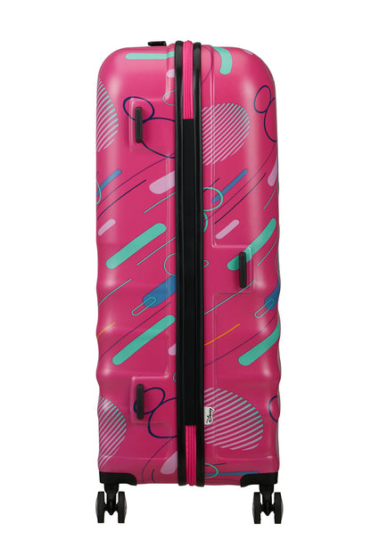 Other side view of the American Tourister Disney Wavebreaker spinner in Pink, showing the zipper and a textured, wave-patterned hardshell. Find Now Online