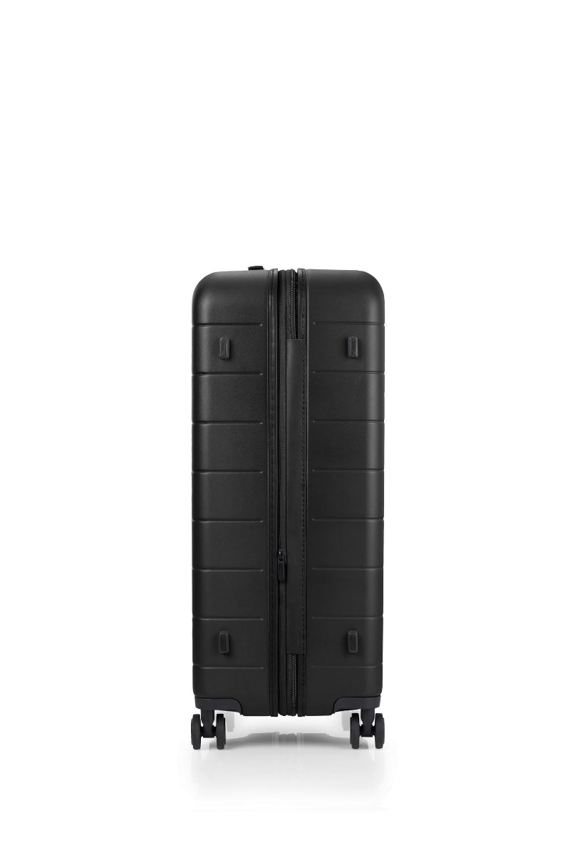 Side view of the American Tourister Novastream Medium hard suitcase Luggage in Dark Slate, with ribbed design, TSA lock, and spinner wheels. Order Online Today